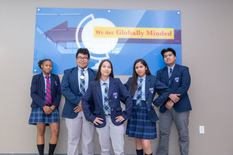 Five Scholars Dressed In School Uniforms Posing Against A Wall