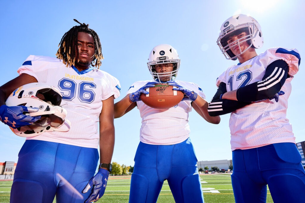 3 Male Football Players Looking Downward At The Camera, Student Athletes From At Best Charter School Texas Education In Dallas, Tx