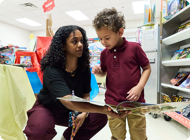 Best Charter School Texas Education Pre-K Scholar Interacting With His Caring Teach To Explore A Book At The Book Fair.